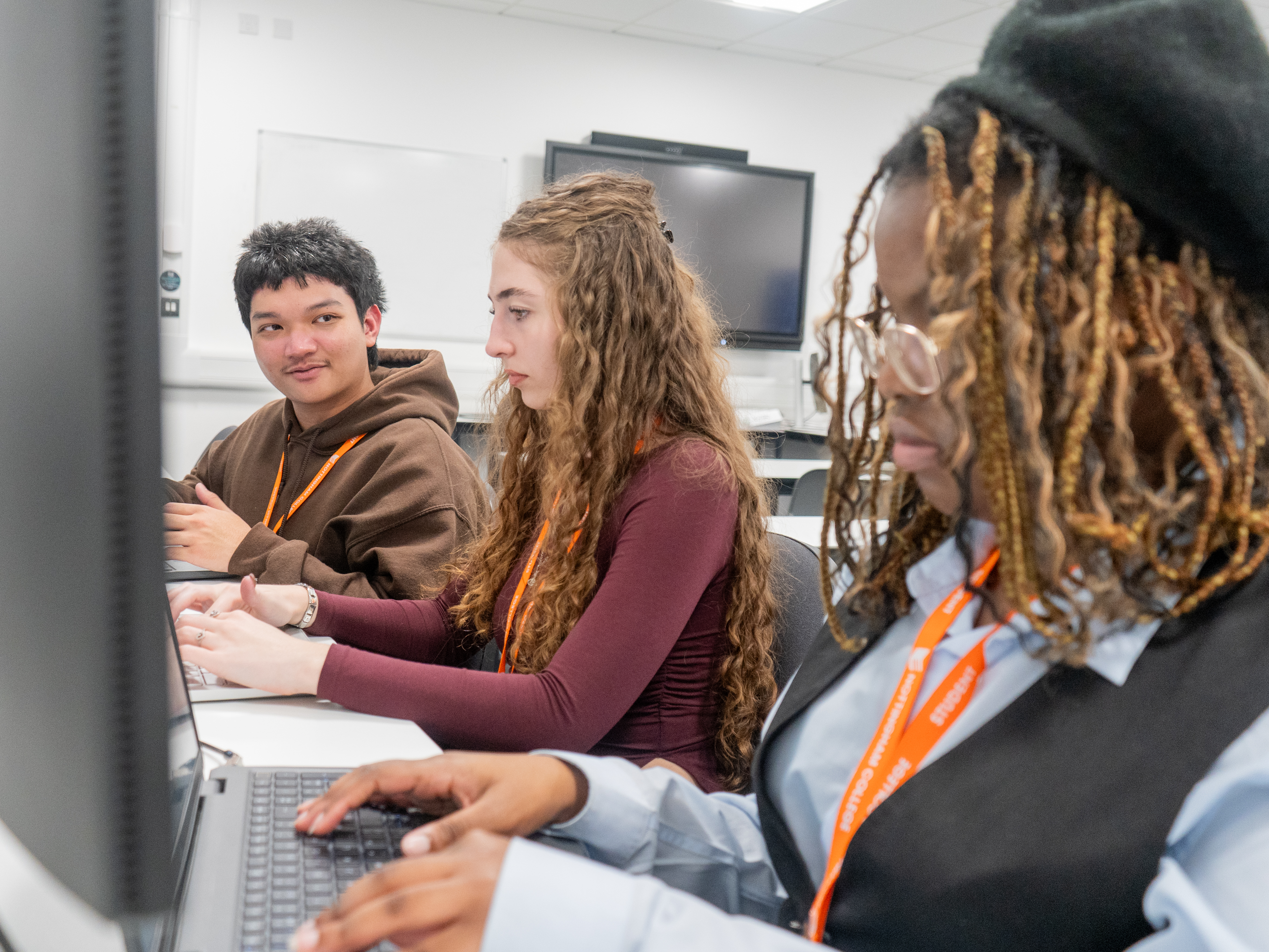3 Business students sat at a desk smiling