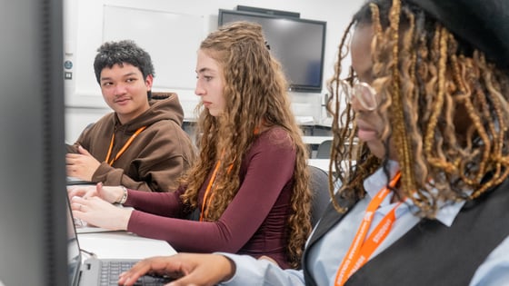 3 Business students sat at a desk smiling