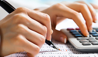 A student writing on a financial statement with a calculator.