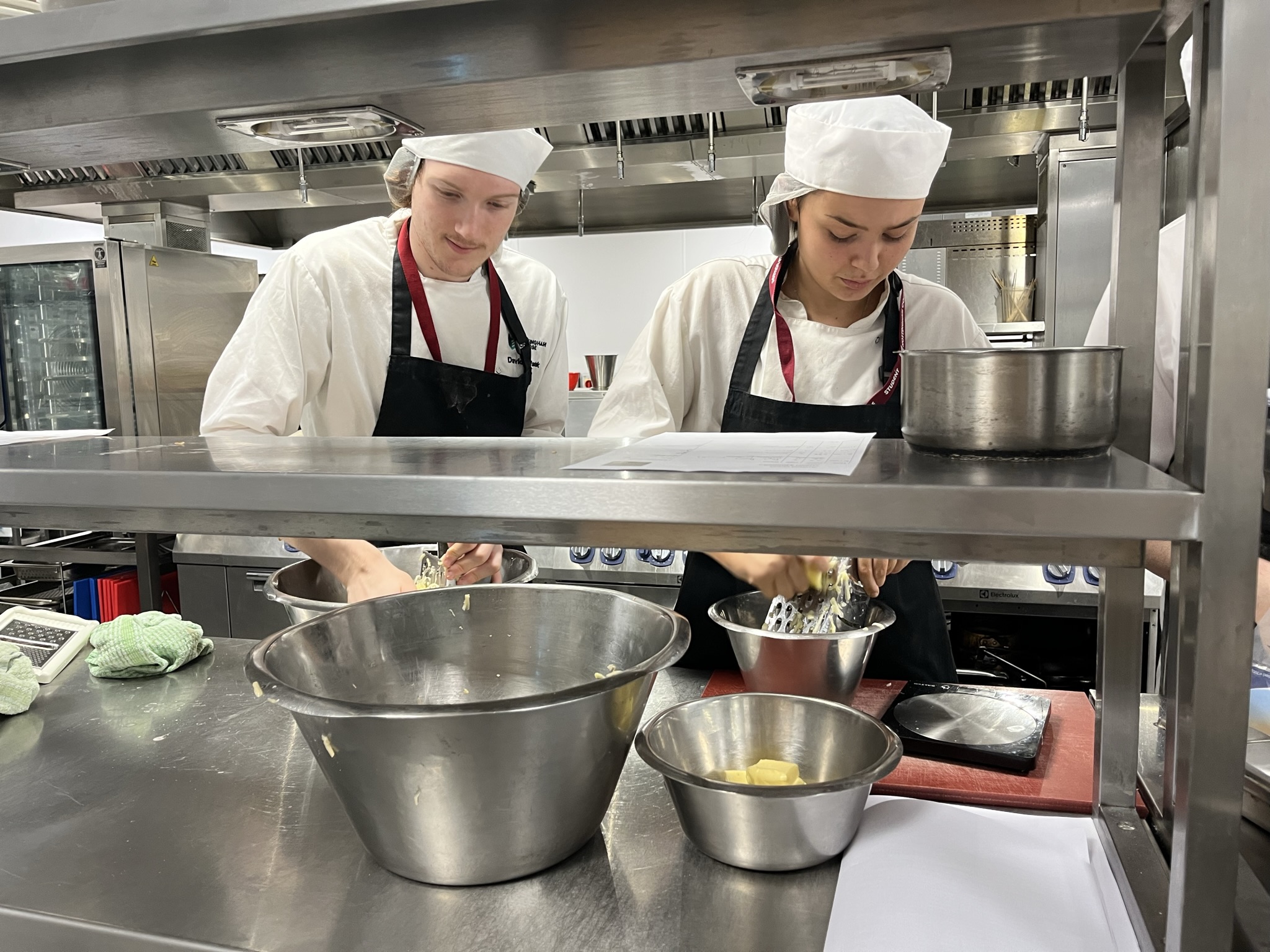 Two catering students preparing food in the kitchen