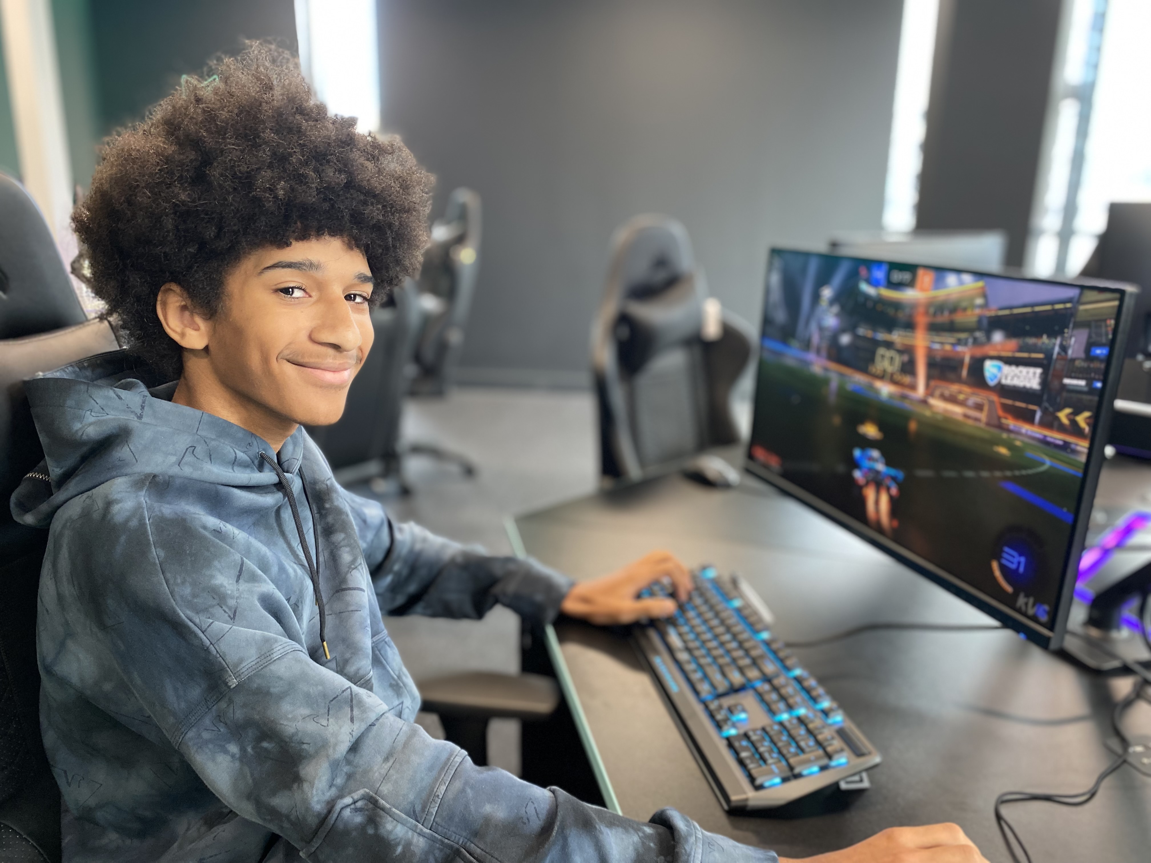 Student sat at a desk with a rainbow lit keyboard and monitor