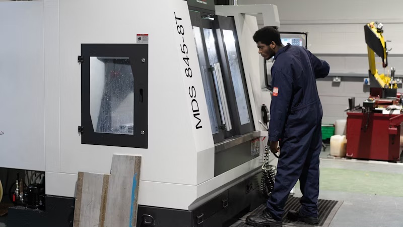 A student operating large machinery in an engineering workshop at Highfields.
