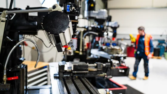Student in a high vis jacket walking around the engineering workshop.