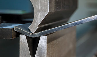 A piece of metal being shaped by a machine.