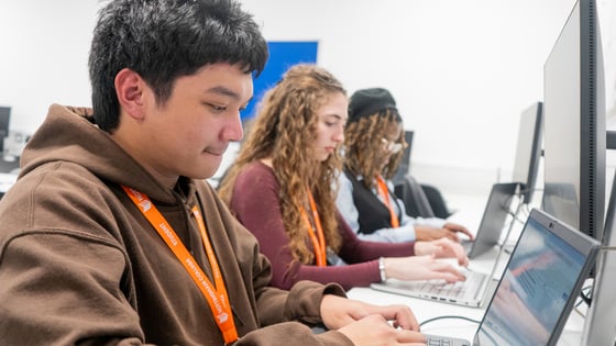 Students working in an IT suite on laptops with screens.