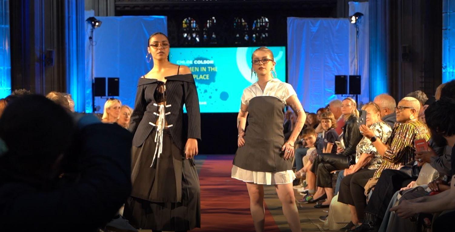 Two students on a catwalk modelling their clothes they designed