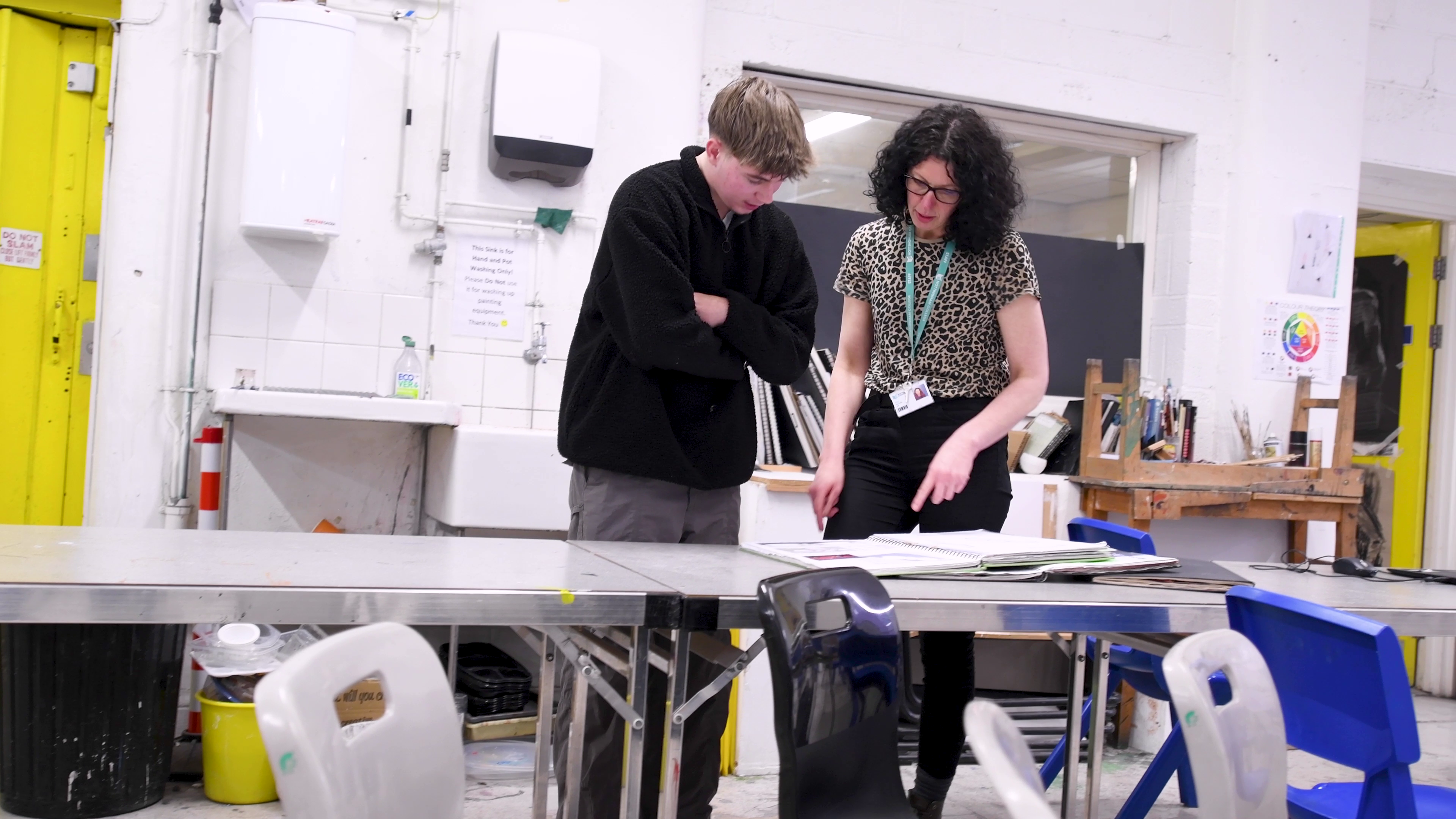 A fashion student talking with their tutor in a classroom