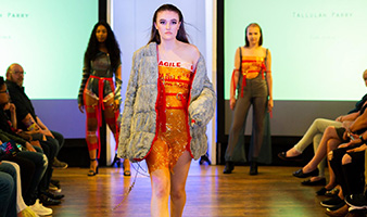 A student on the catwalk wearing clothes designed by students