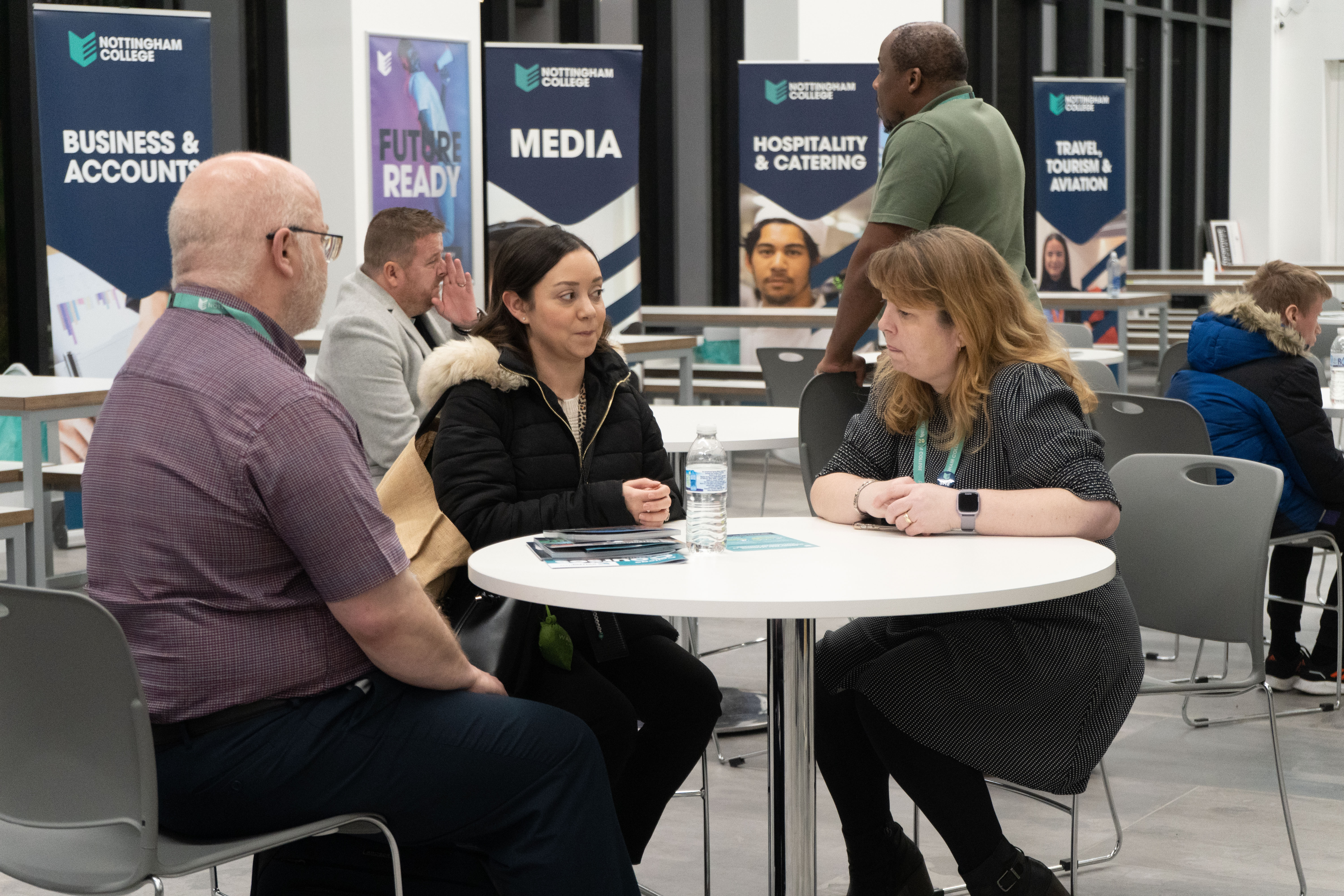 A student talking to two members of staff at an open evening