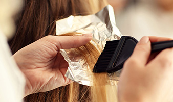 A client holding part of a clients hair with foil applying colour
