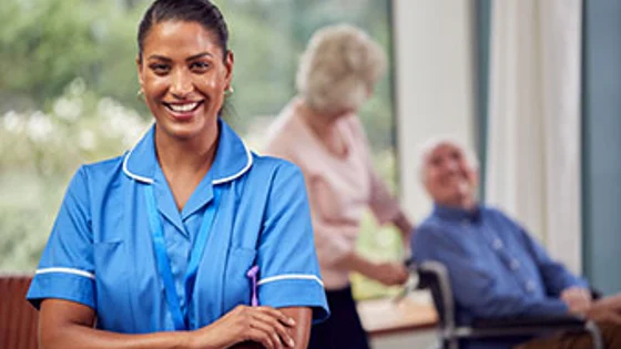 An adult care worker with older people in the background.