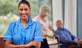 An adult care worker with older people in the background.
