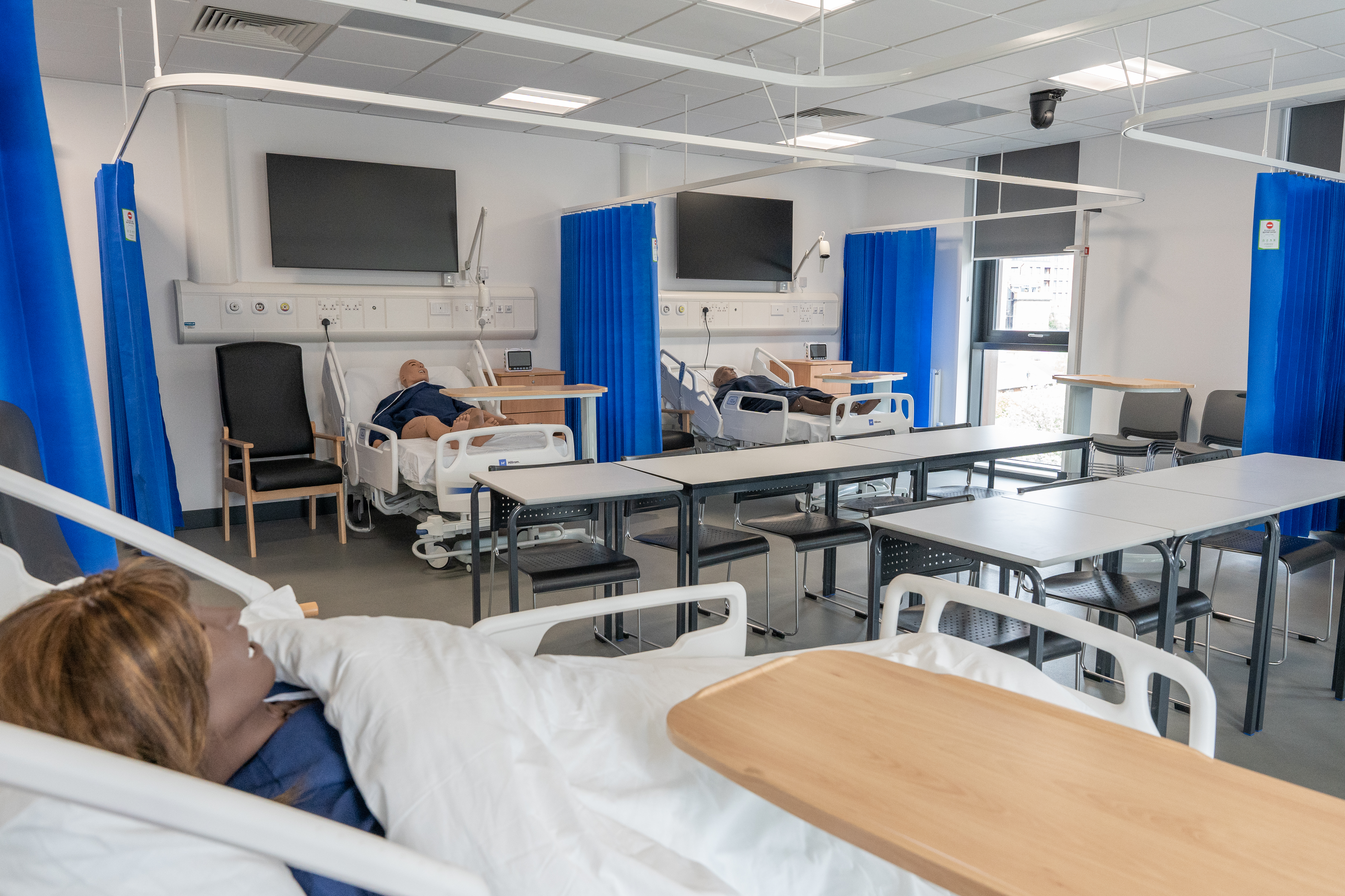 A simulated hospital ward with hospital beds and dummies to practice on.