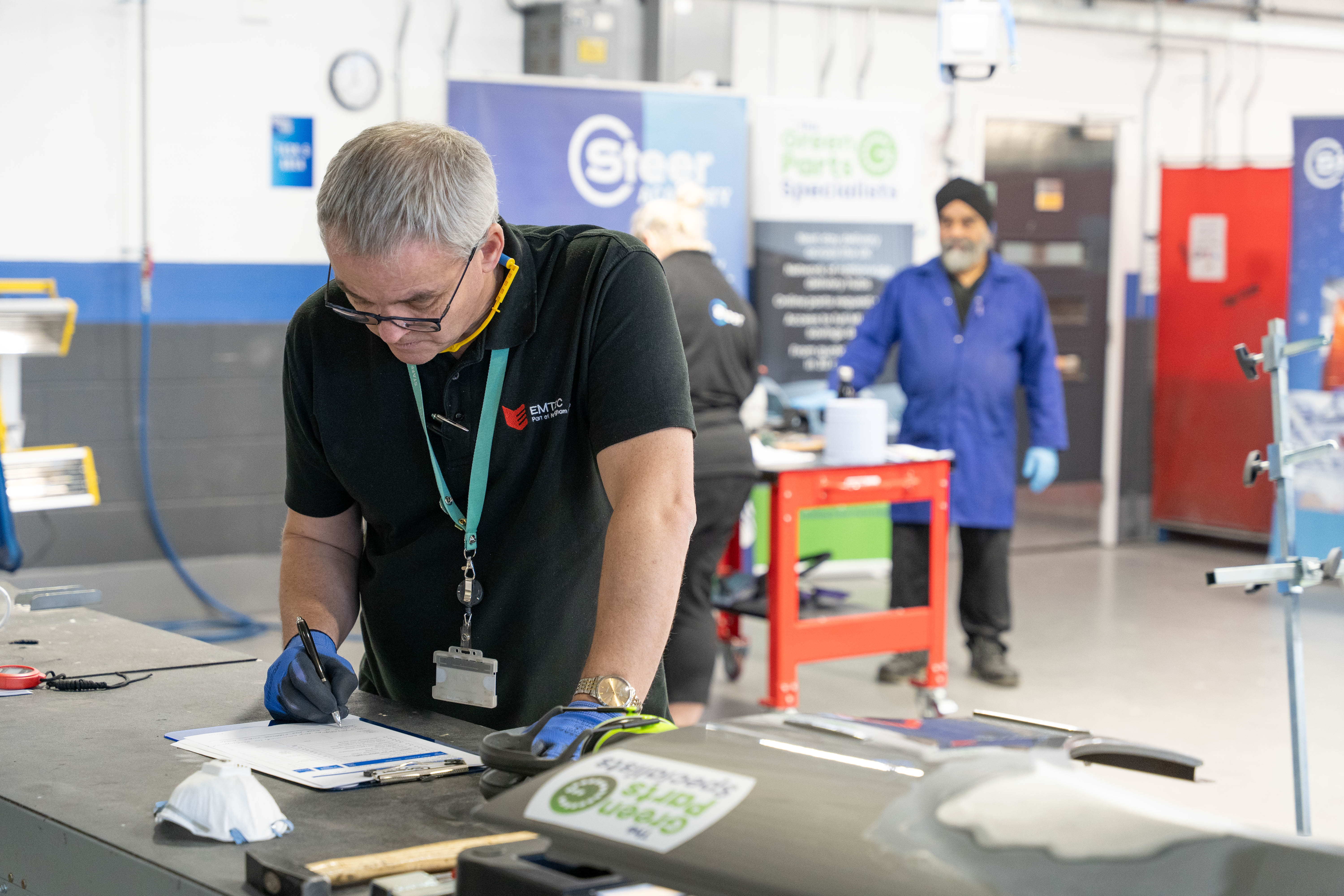 An vehicle assessor making notes in an automotive workshop.