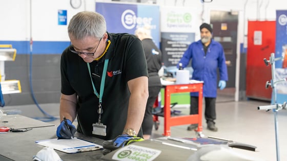 An vehicle assessor making notes in an automotive workshop.