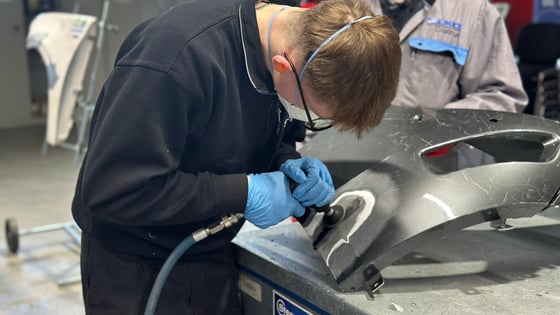Male student working on a car body part