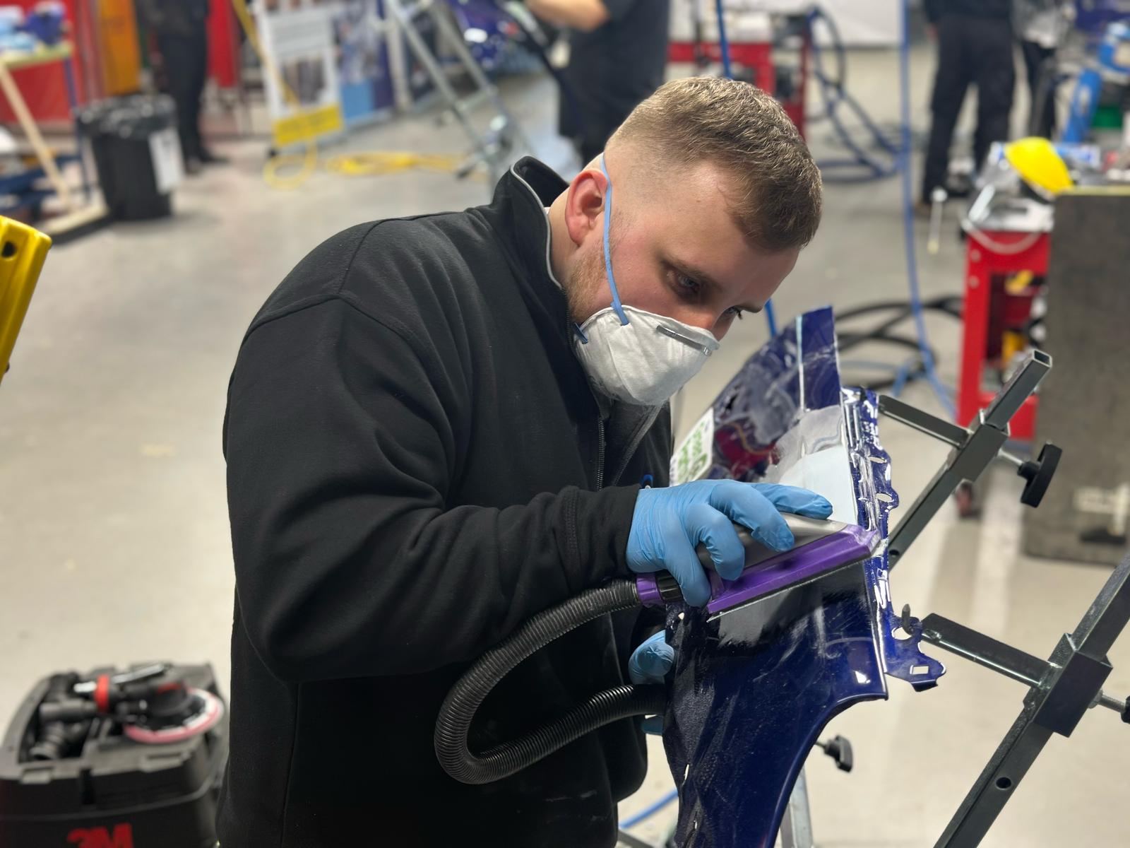 Male student working on a car body part