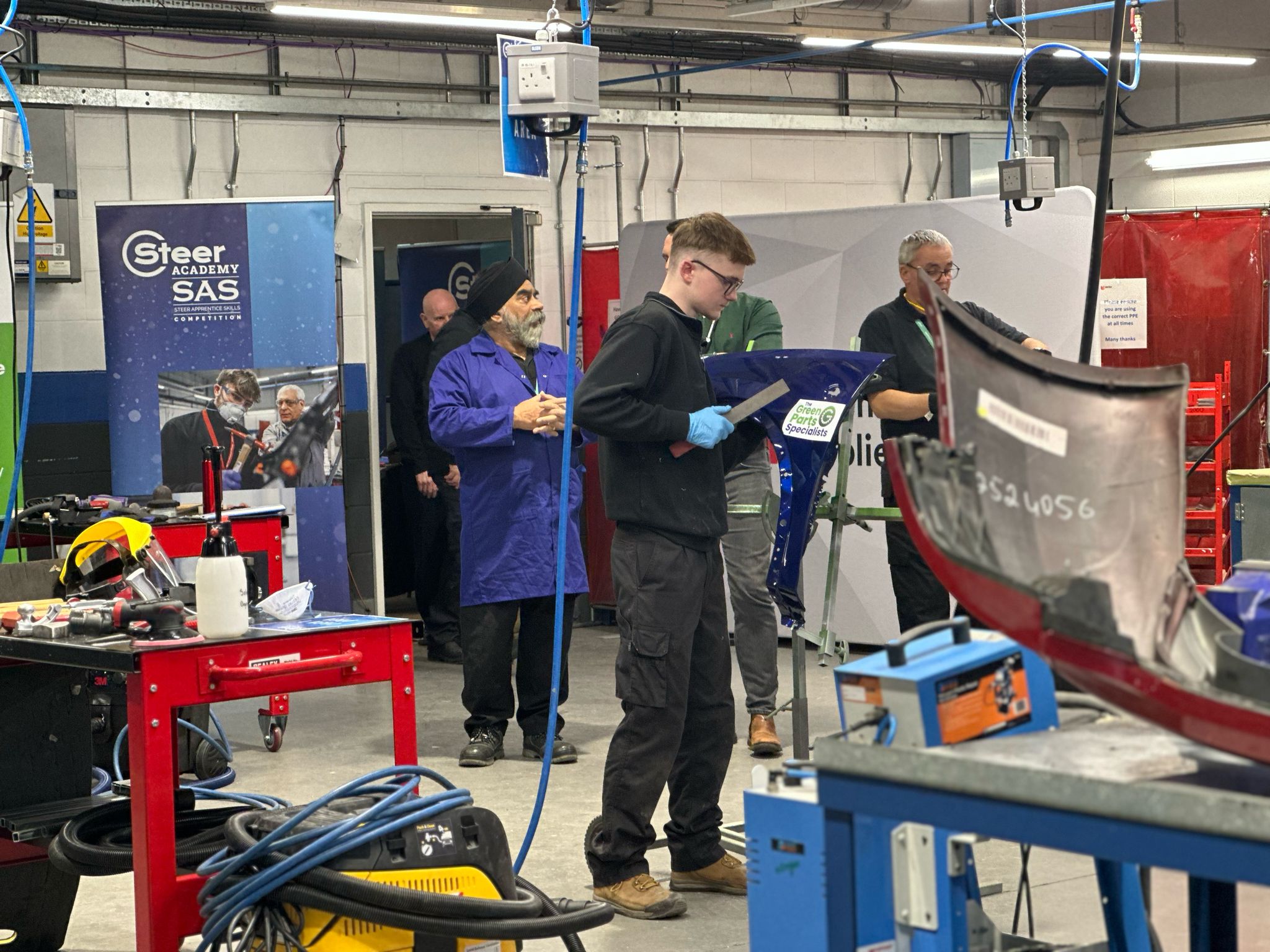 Students working in a workshop on car body parts.