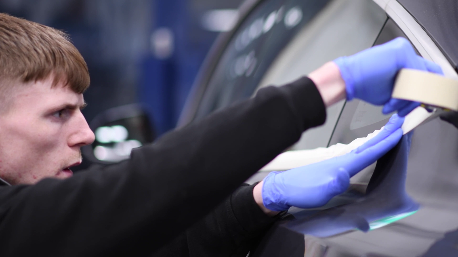 Motor vehicle student applying tape to a car