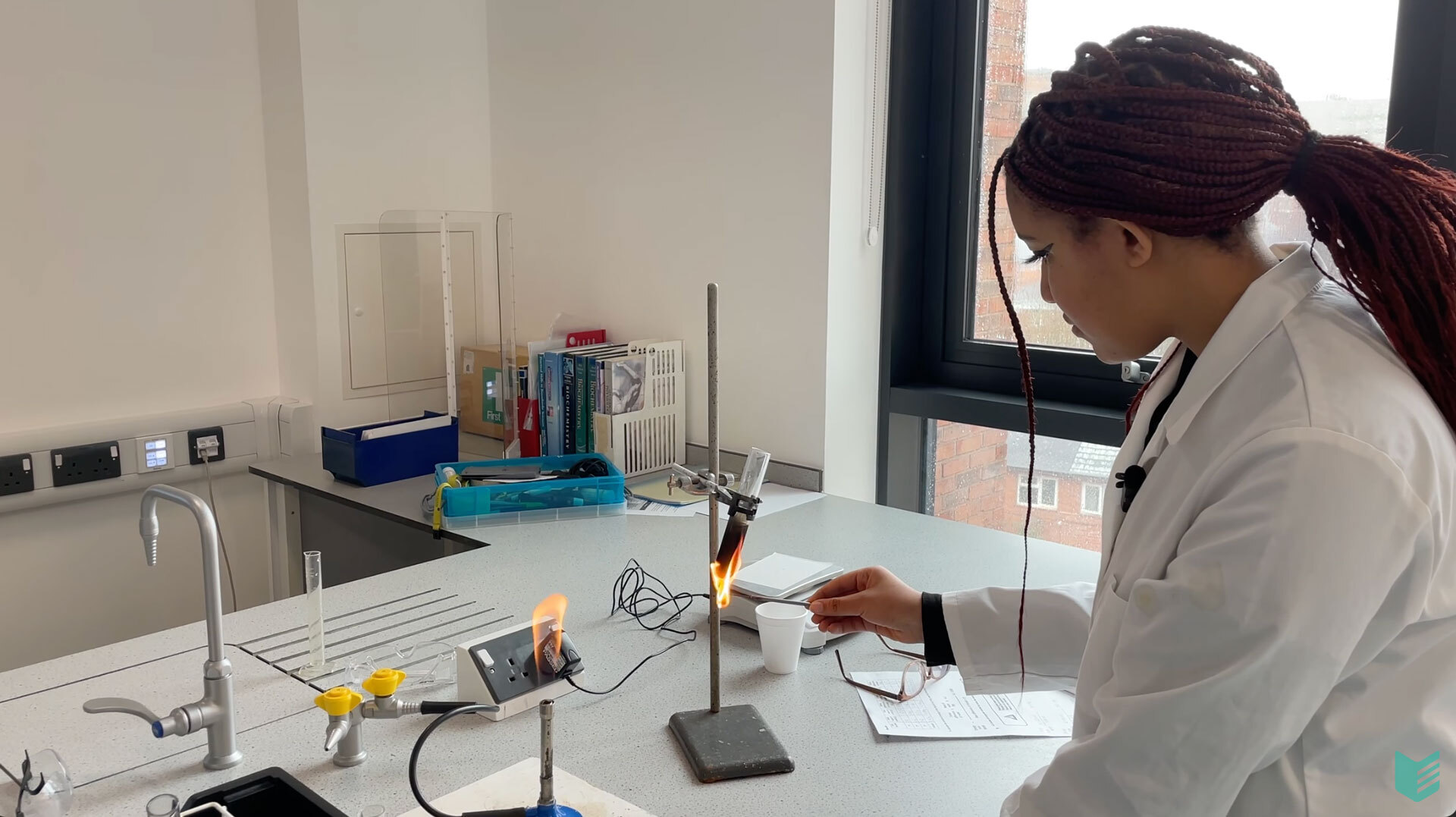 A student using a Bunsen burner in a science lab.