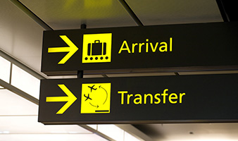 A picture of a board at an airport pointing to arrivals and transfers.