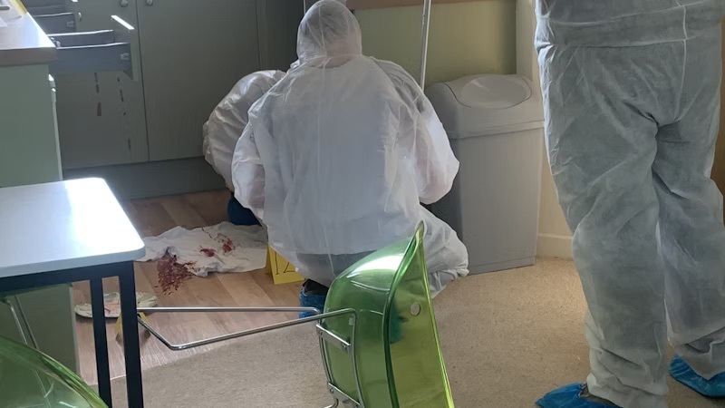 Students in protective clothing taking samples at the crime scene house.