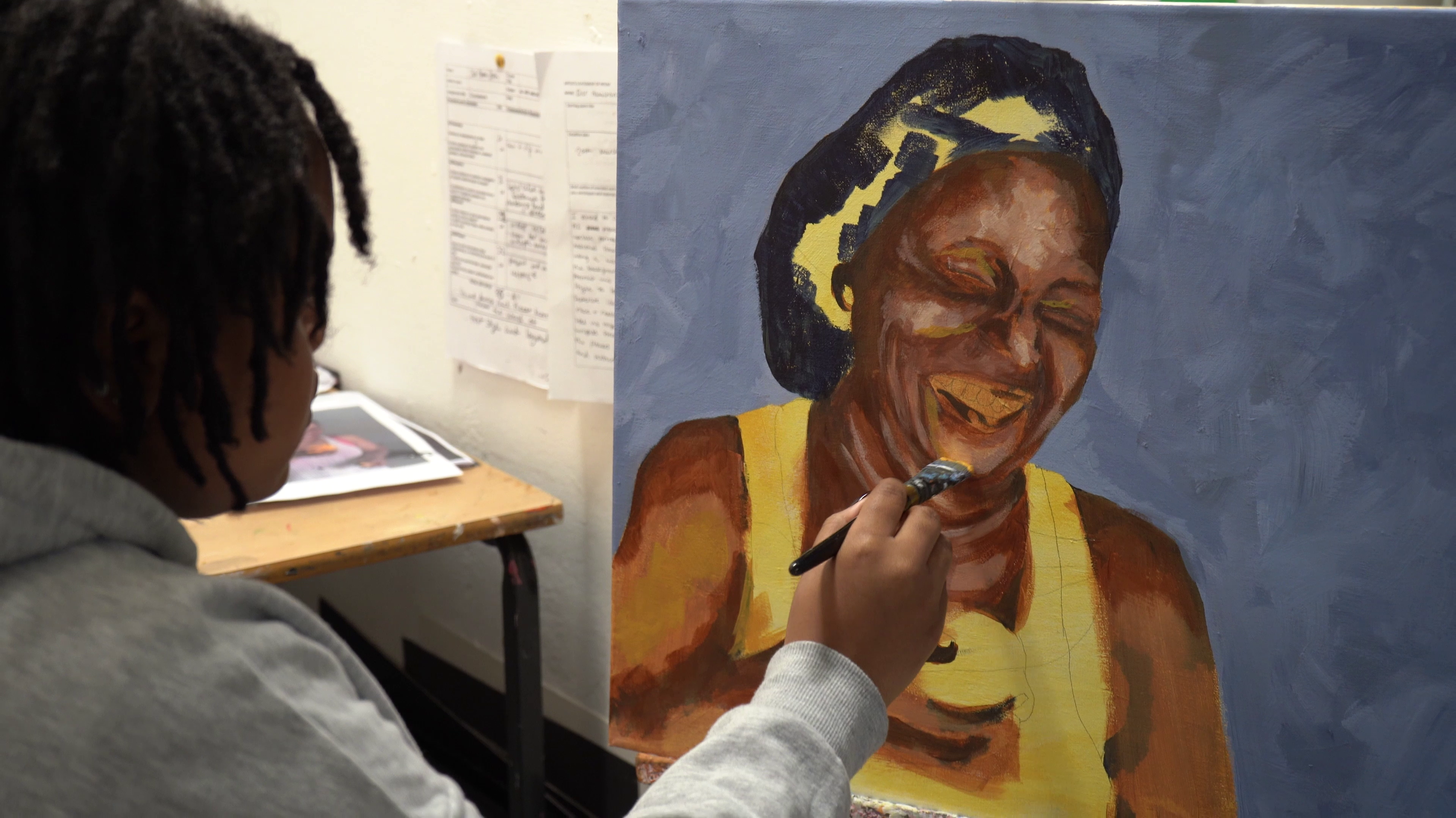 An art student painting a picture of a person smiling
