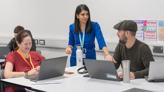 Adult students in a classroom with laptops with a lecturer