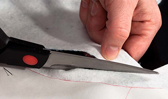 A person cutting interfacing with a pair of scissors