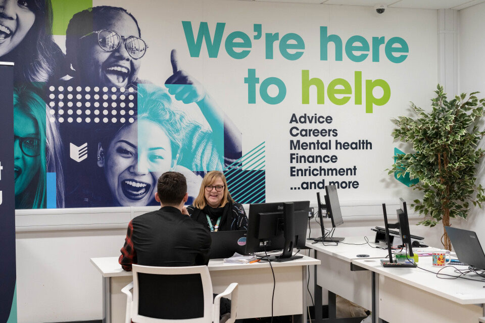 A student being helped by a member of staff in student services