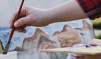 A person using watercolours to paint a landscape.