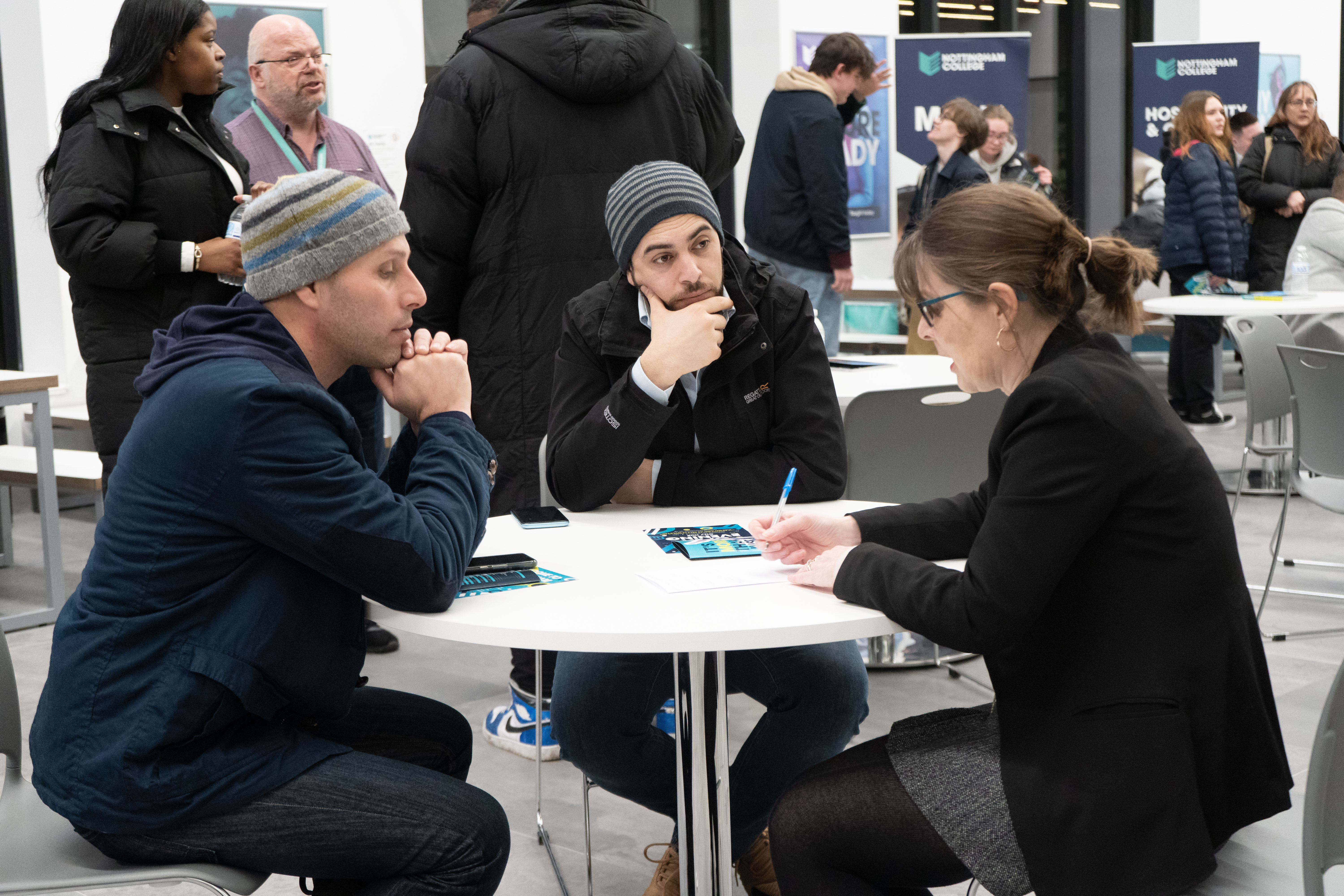 Two adult students talking to a member of staff