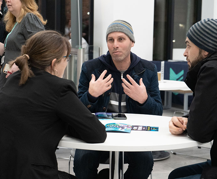 Adults talking around a table at an open evening.