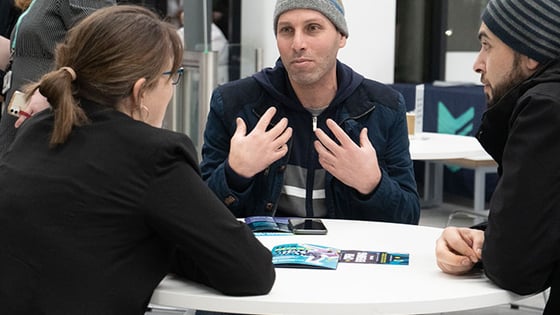 Adults talking around a table at an open evening.