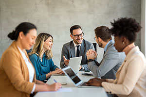 A group of people sitting around a desk having a meeting.