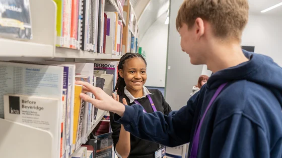 Two sixth form students smiling at each other in the library