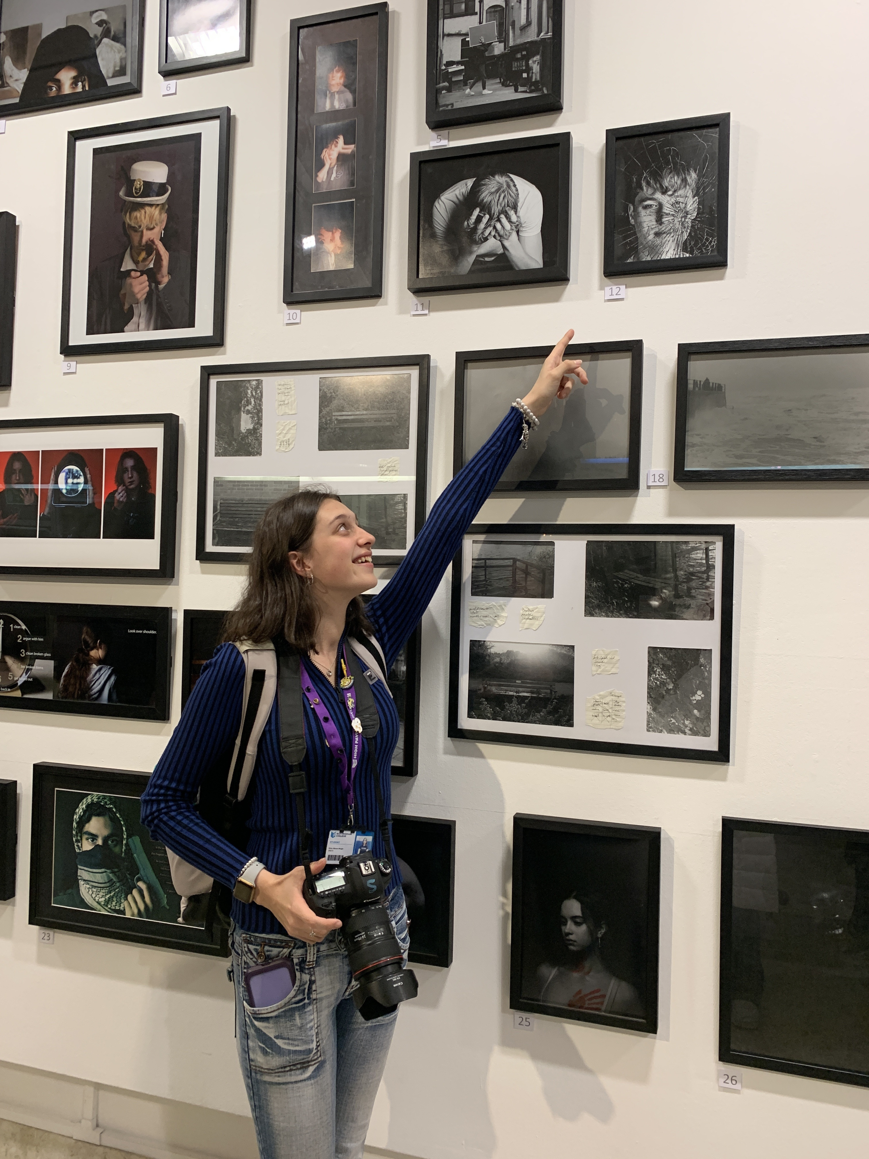 A student pointing at a picture with a gallery behind her