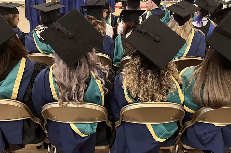 The back of several graduates sitting in the Albert Hall for a graduation ceremony