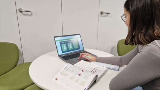 A young student studying A Level biology with a textbook open and laptop