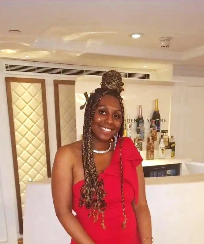 black woman in braids with a formal red dress and silver necklace smiling at the camera