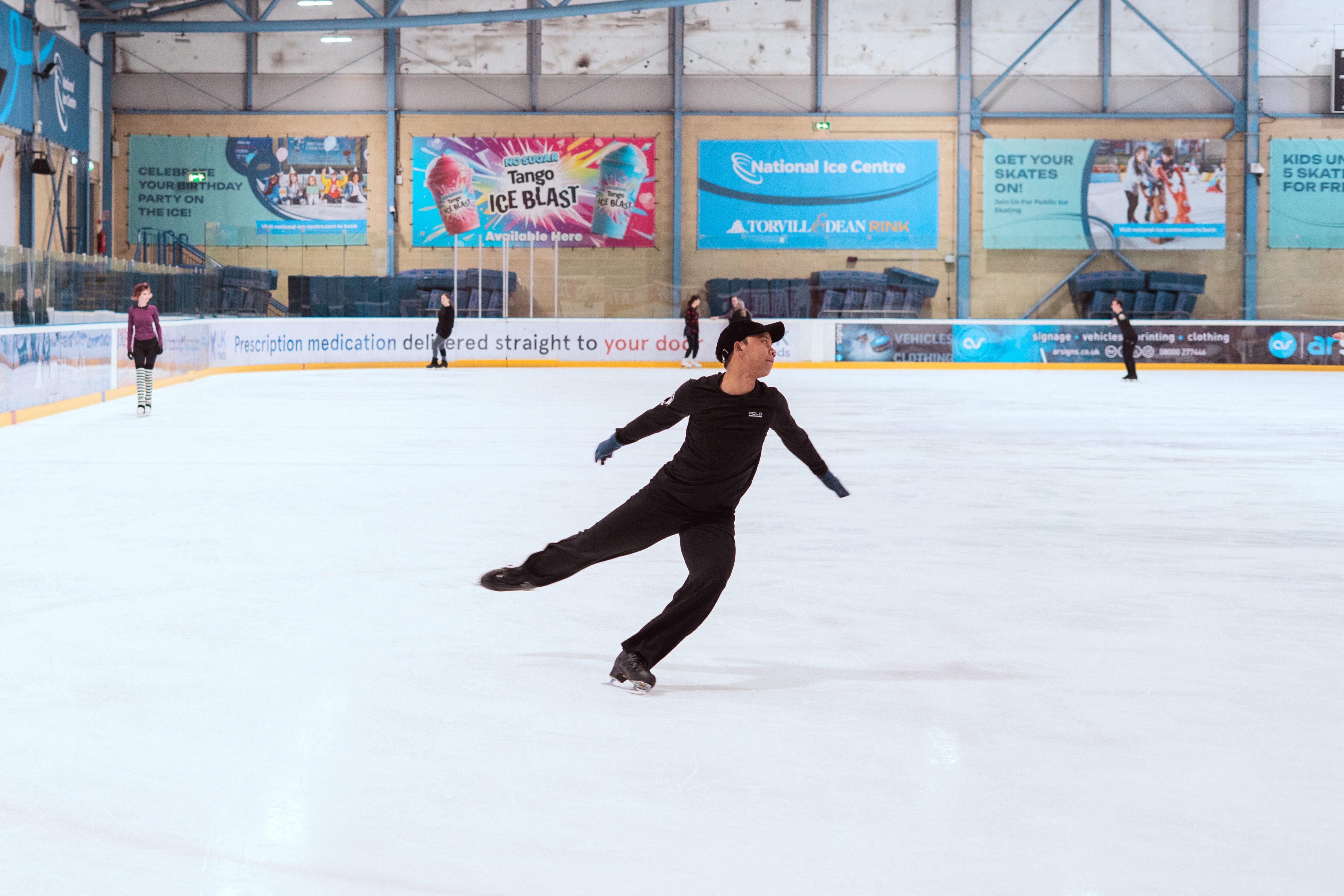 Hanyu skates and twirls on the ice with his arms out and one leg in the air.