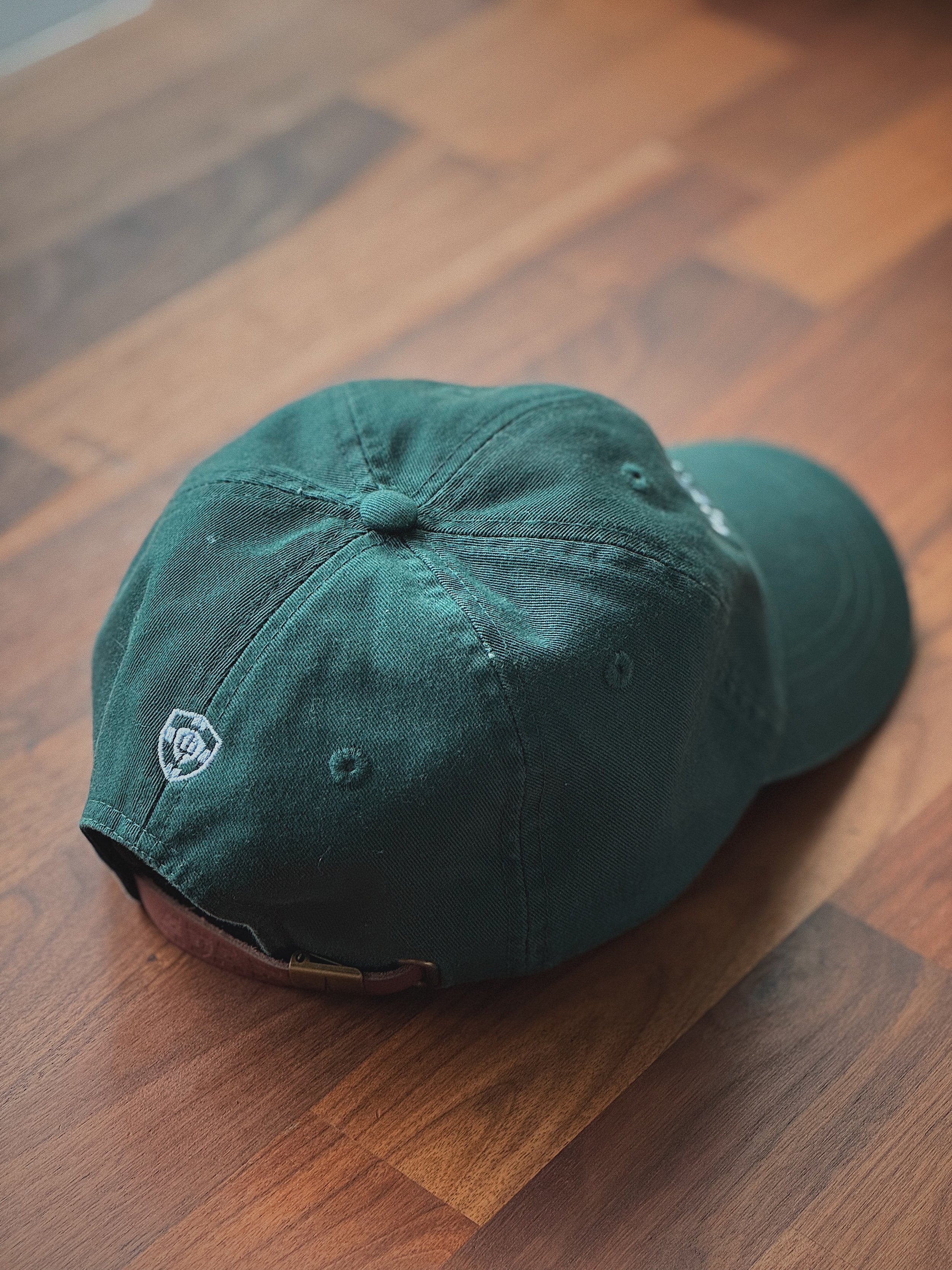 Back of a green Greenville Seminary baseball cap featuring an embroidered crest.