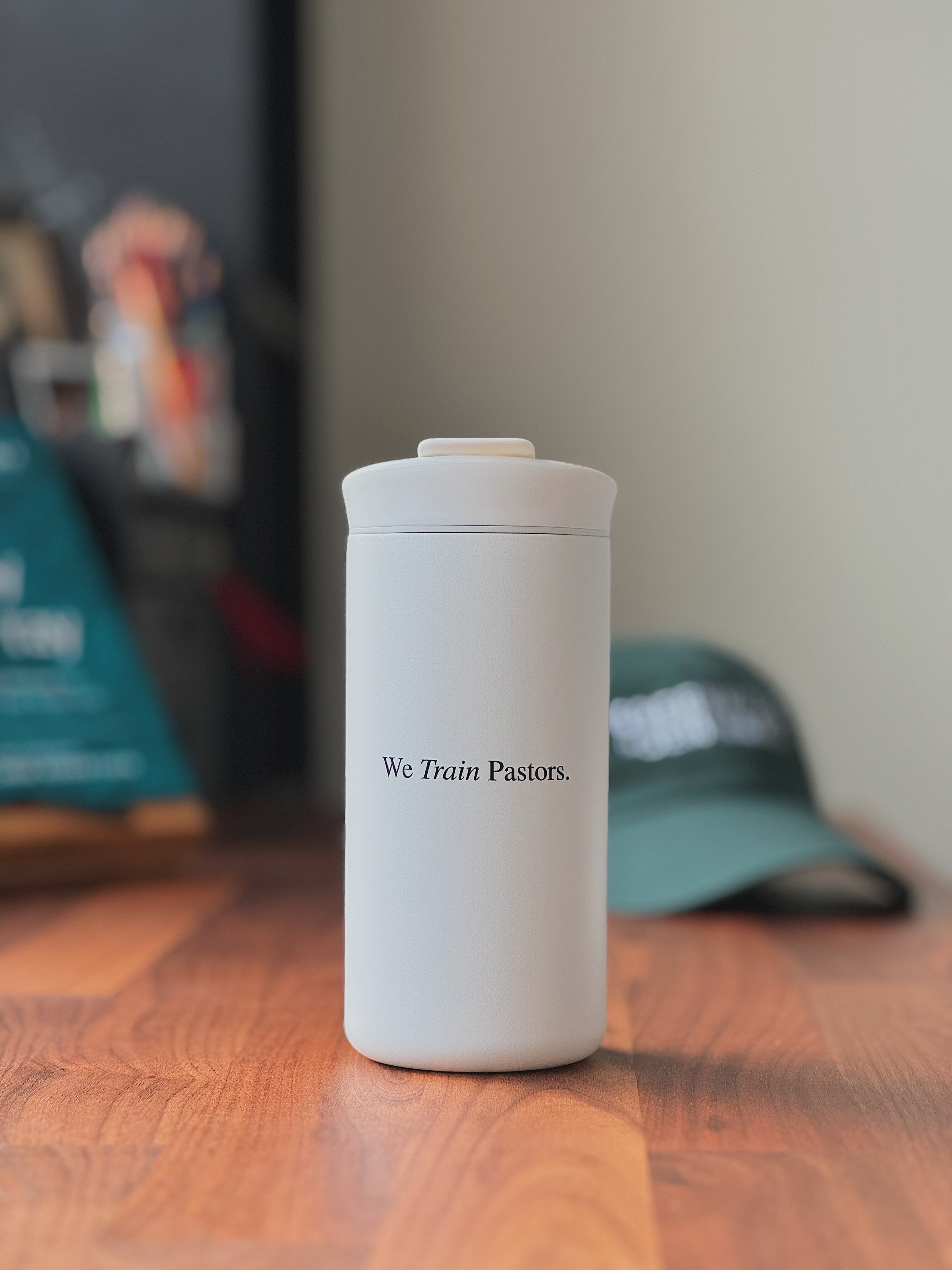 White insulated tumbler printed with the phrase ’We Train Pastors.’