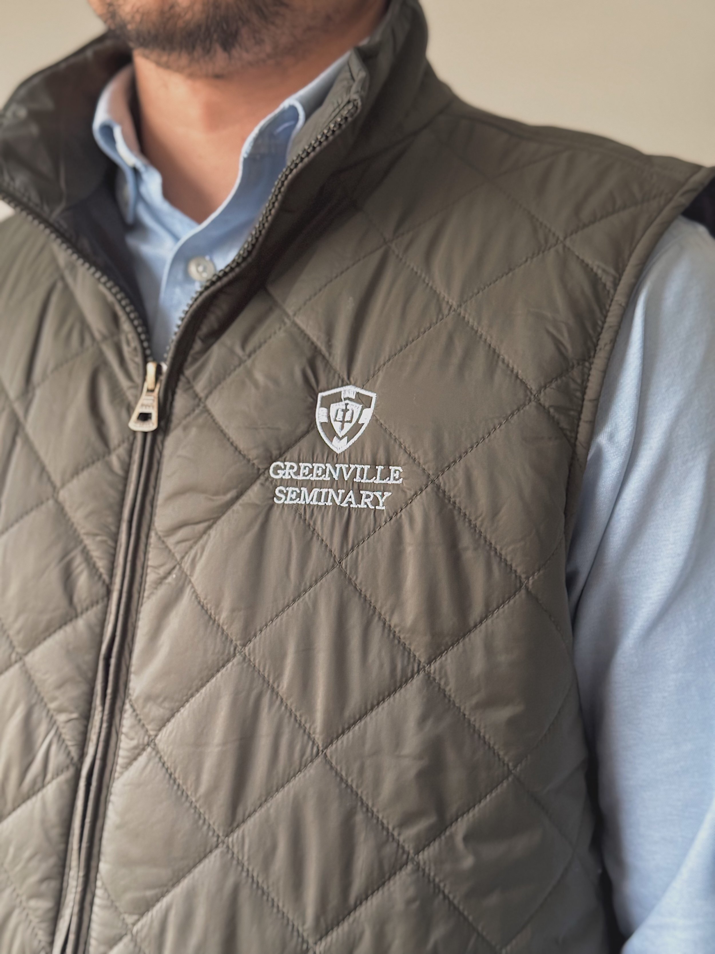 Close-up view of the quilted vest showing the Greenville Seminary embroidery.