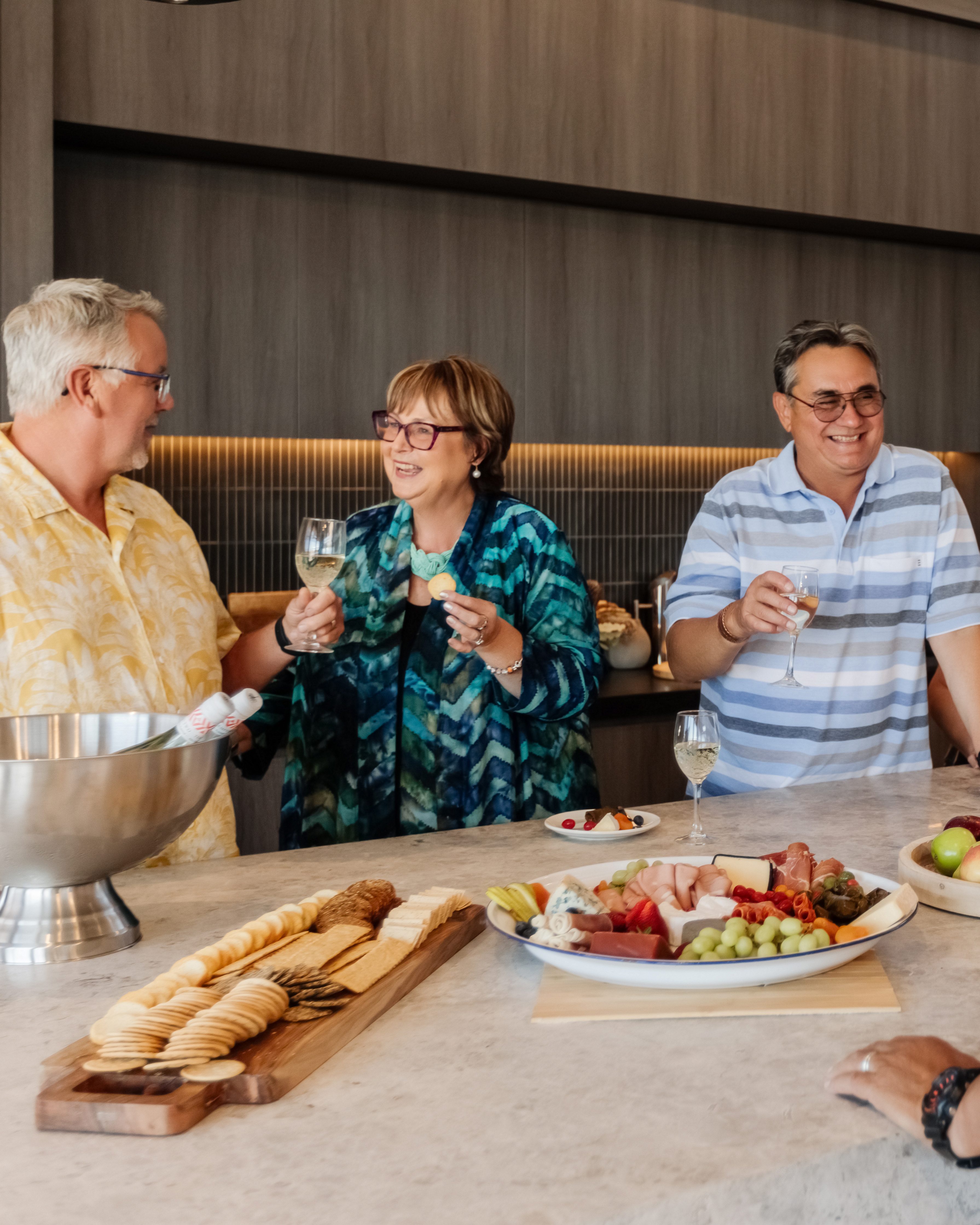 Three friends enjoying wine and charcuterie together in a modern community kitchen.”