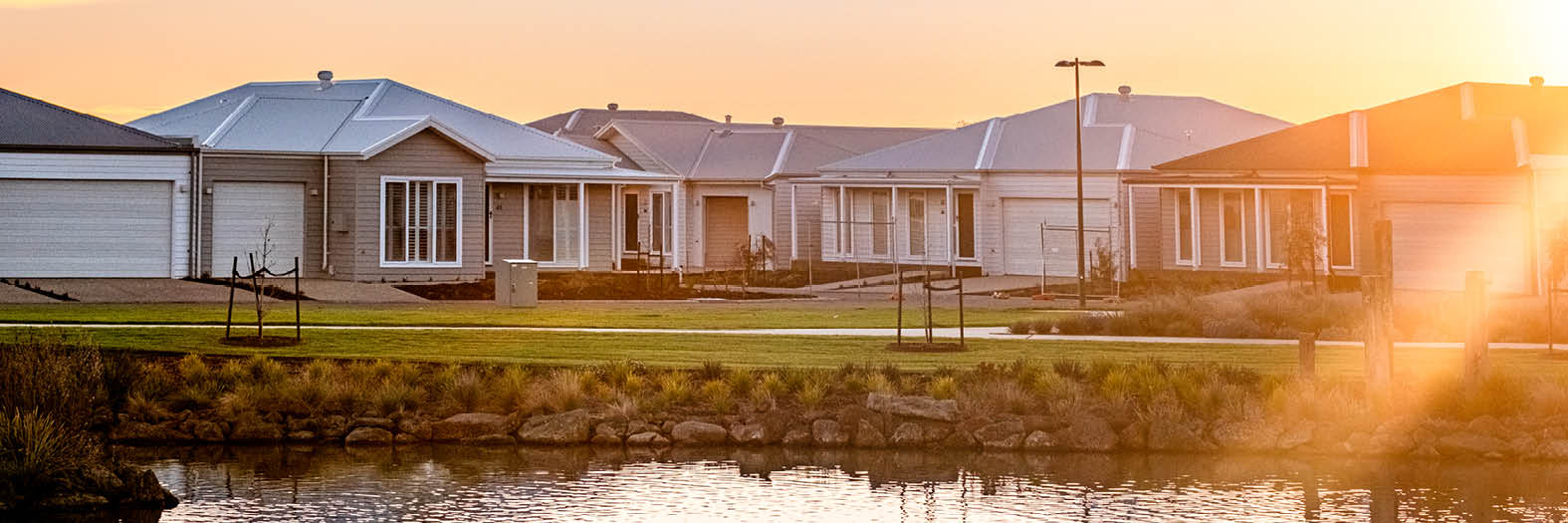 Modern homes at Lifestyle Communities Bellarine beside a calm lake at sunset