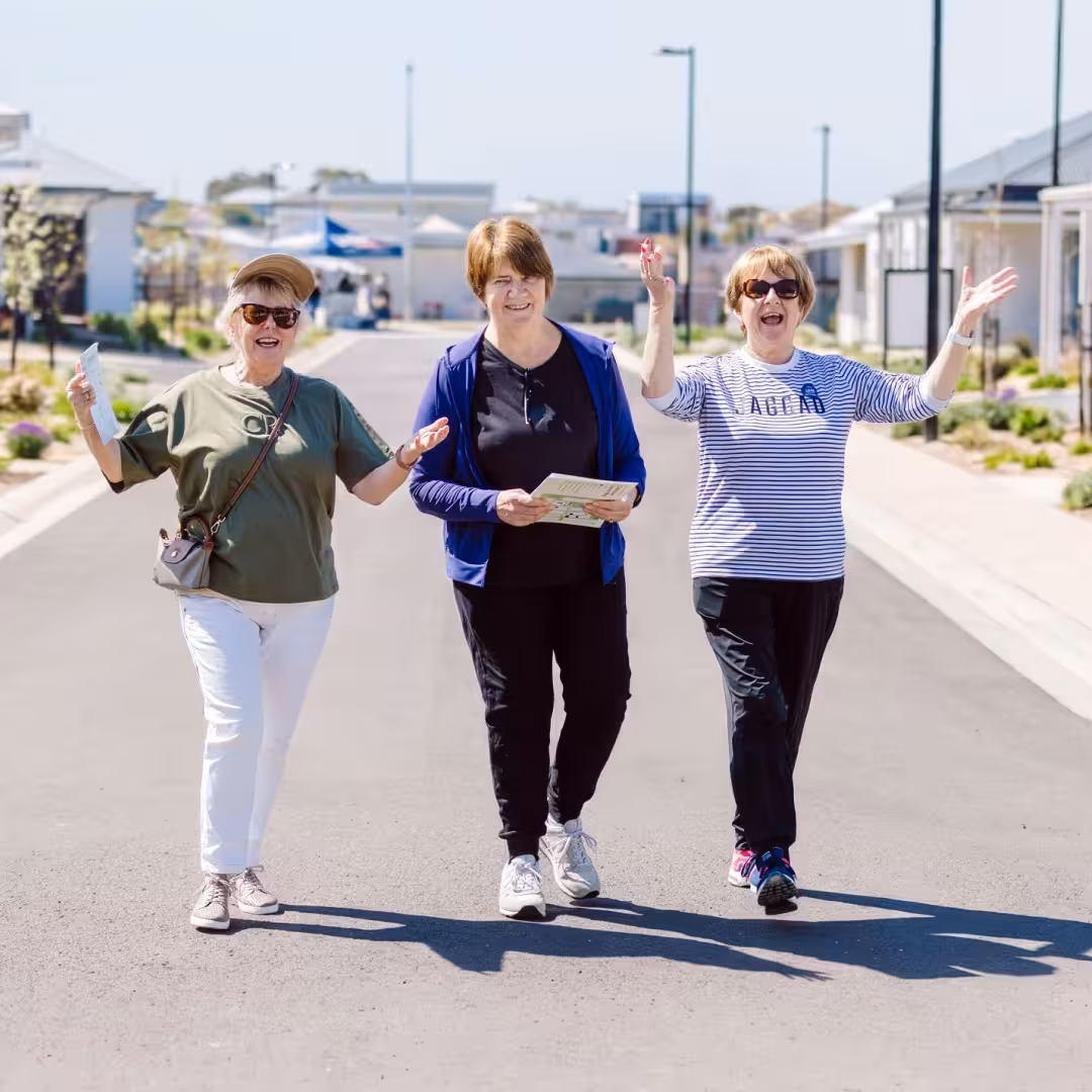 Three visitors walking along a residential street during a community open day, holding event materials while exploring the neighbourhood.