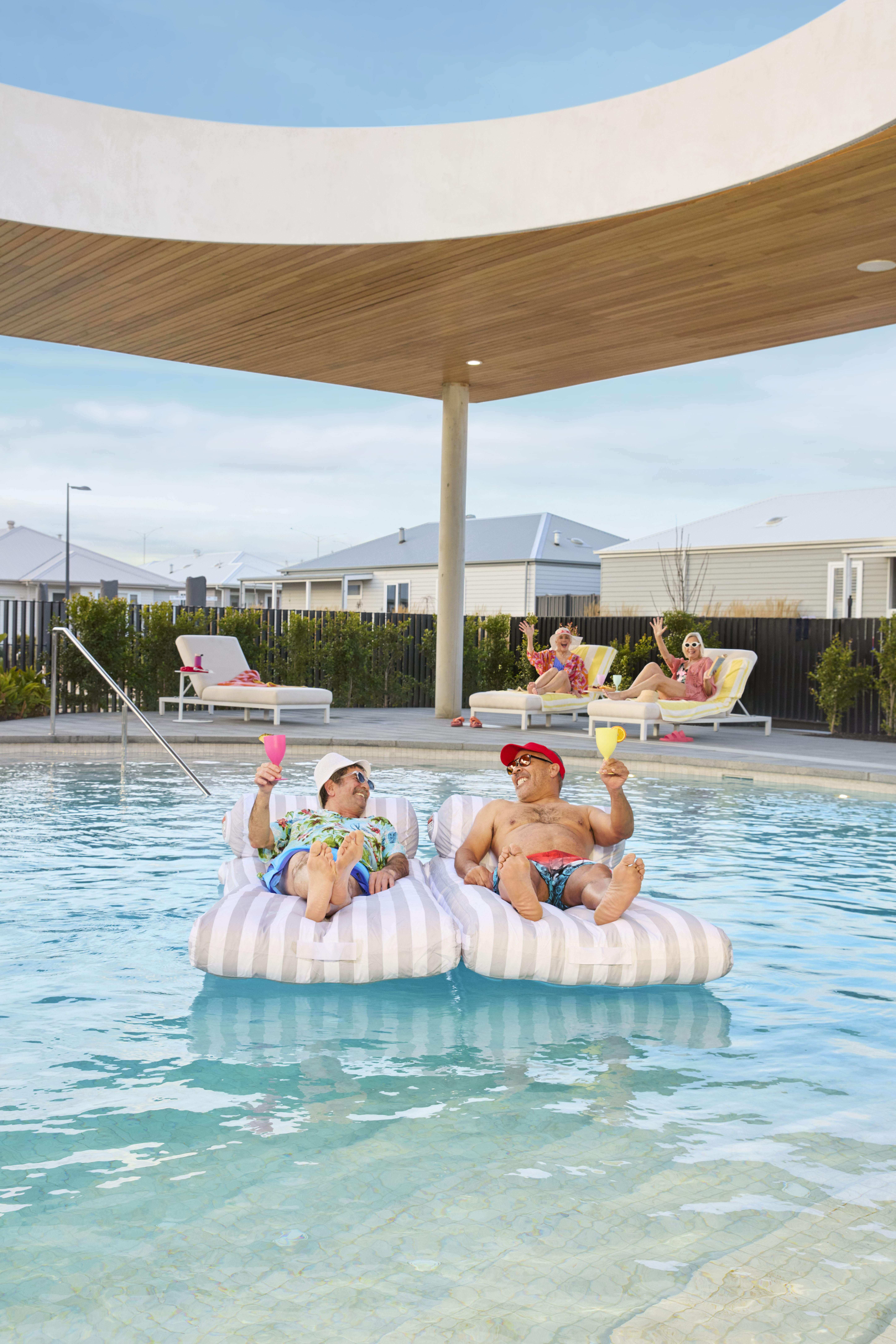 Residents relaxing on pool floats and enjoying drinks at the Lifestyle Communities resort-style pool.