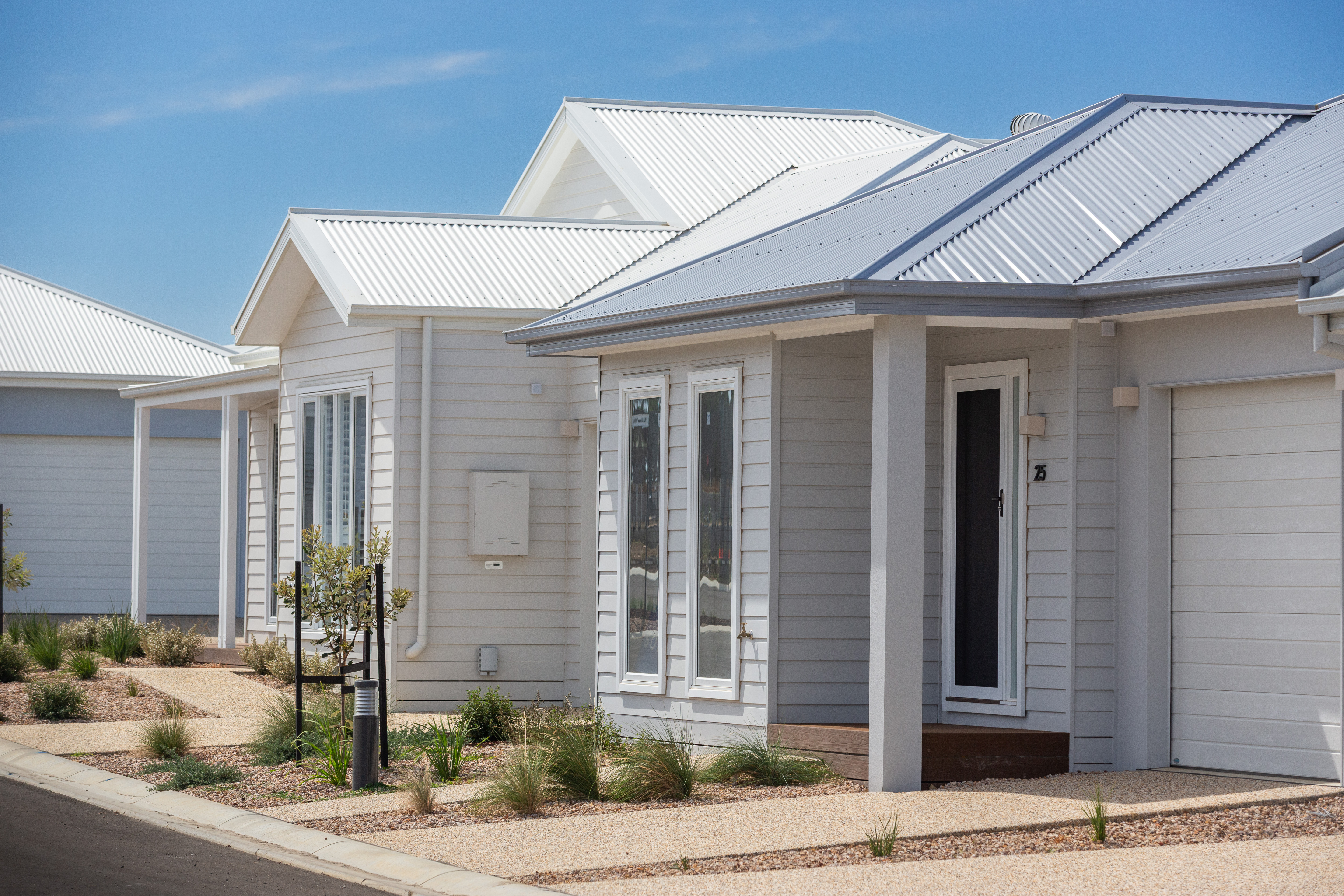 Single-storey lifestyle home with light cladding, roof, garage and landscaped front yard in a residential community.