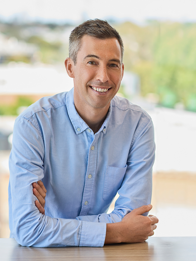 Individual wearing a light blue button-up shirt with arms crossed.